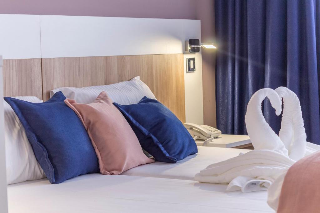 a bed with a bunch of pillows and a swan on it at Airport Hotel Garni in Belgrade