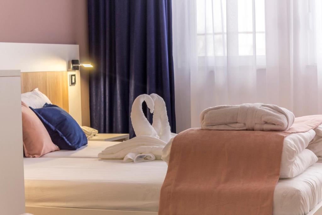 a hotel room with a bed with towels on it at Airport Hotel Garni in Belgrade