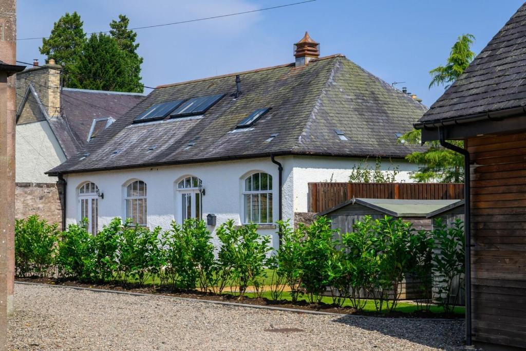 a white house with a black roof at The Coach House in Alyth