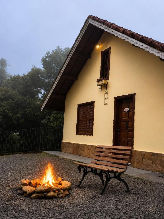 a fire pit with a bench in front of a house at Recanto da Neblina in Monte Verde