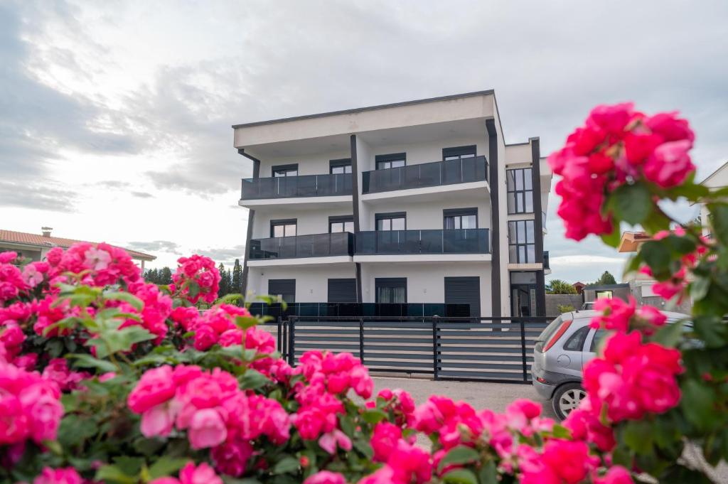 a building with pink flowers in front of it at Nejla Apartmani Stoj in Ulcinj