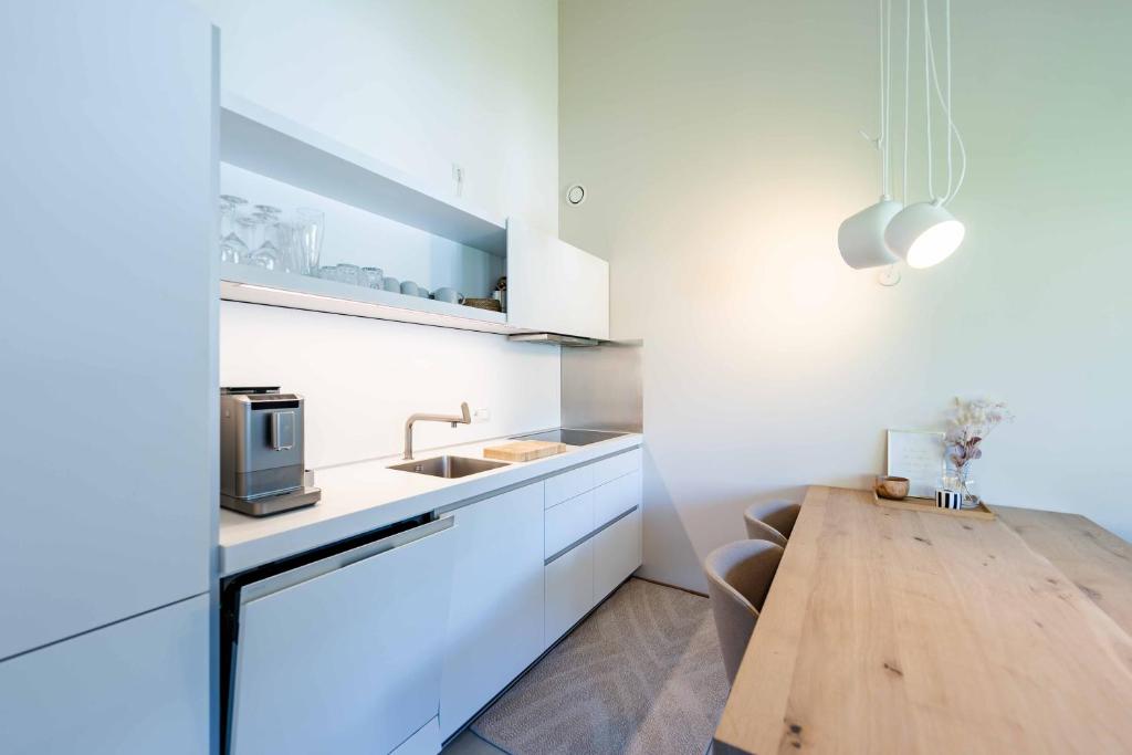 a kitchen with white cabinets and a wooden table at hus9 in Mittelberg