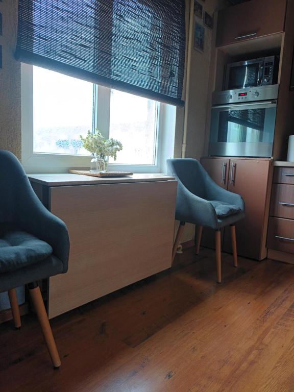 a kitchen with two chairs and a desk and a window at 2 precu 17 in Daugavpils