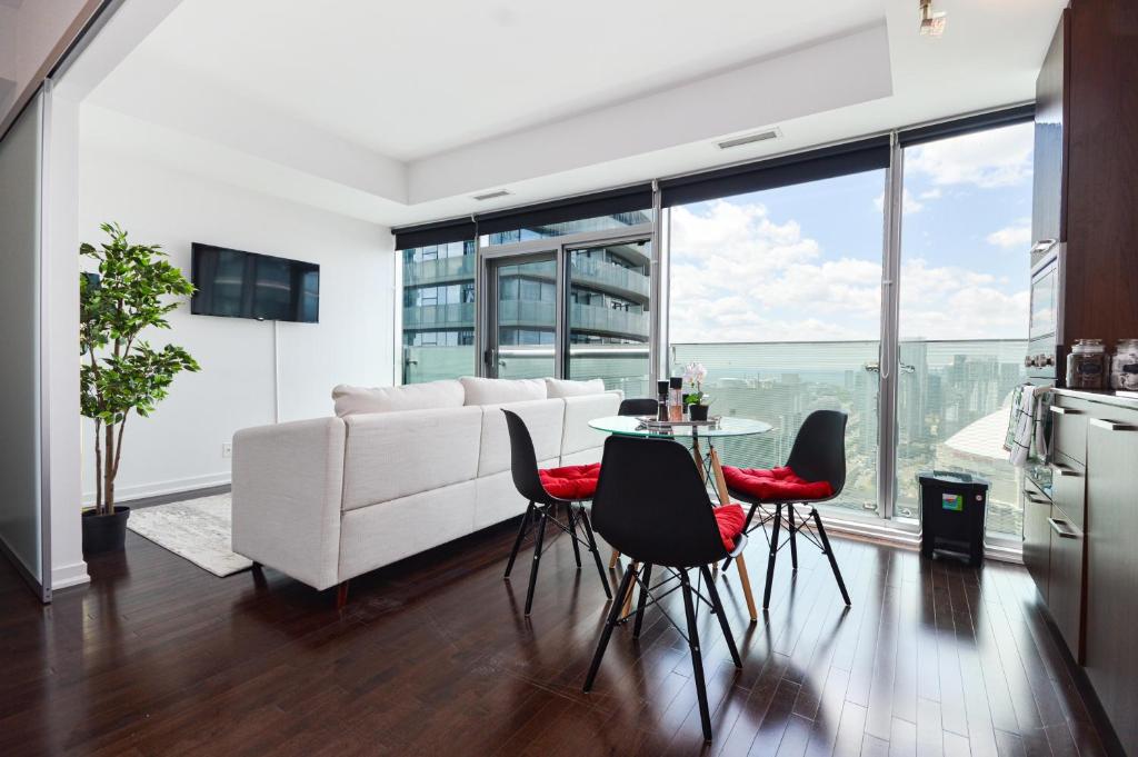a living room with a white couch and a table and chairs at Downtown Toronto CN tower Condo in Toronto