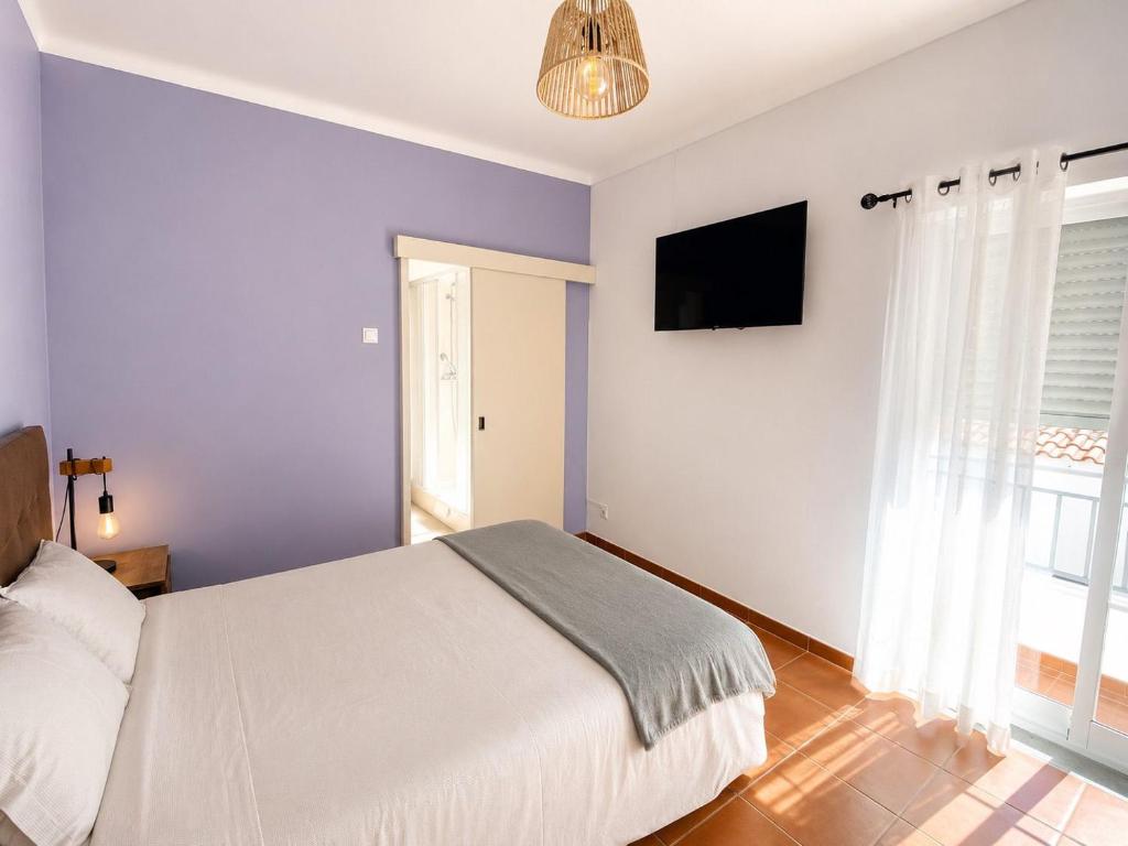 a bedroom with a bed and a flat screen tv at Apartamento Vicentino in Vila Nova de Milfontes
