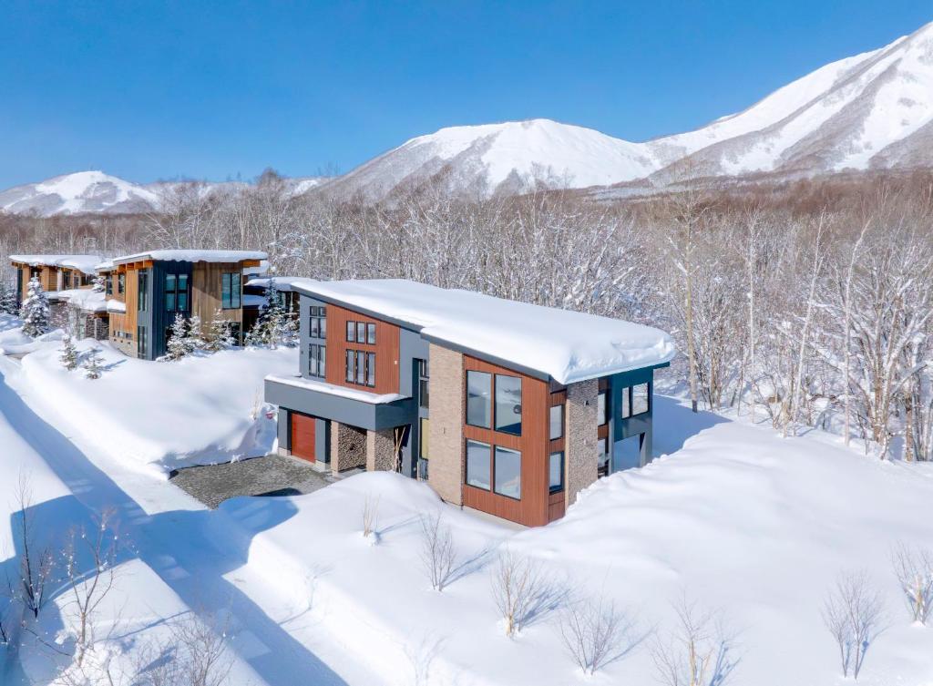 a home in the snow with mountains in the background at Rose - Rusutsu Chalets in Kimobetsu