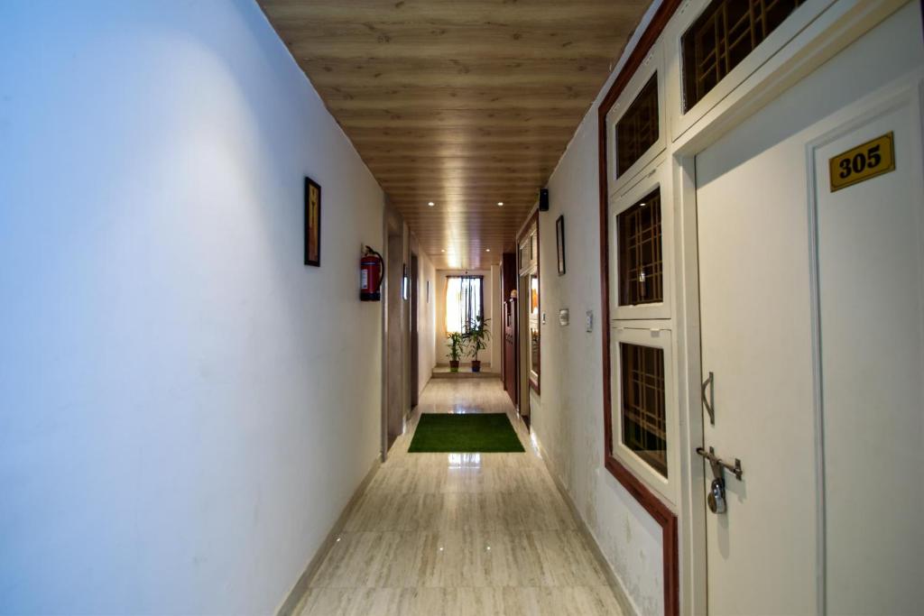 an empty hallway with a door and a green rug at Hotel O Kanchan Residency in Kota