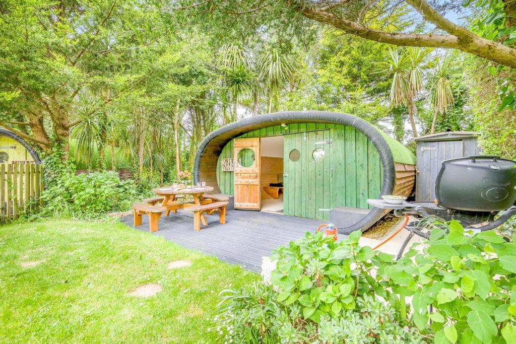 a backyard with a green shed with a table and a tv at 1 Bed in Bude oc-s34857 in Bude