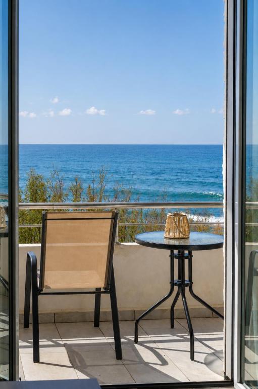 a table and a chair on a balcony with the ocean at Sole e Mare B1 Beachfront Sea View Apartment in Koutsourás