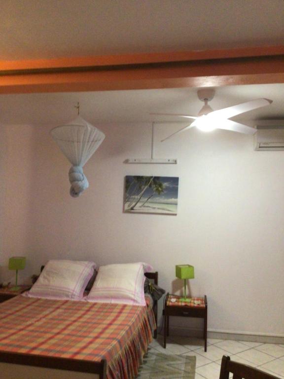 a bedroom with a bed and a ceiling fan at Philippe & Arlette SMITH in Sainte-Luce