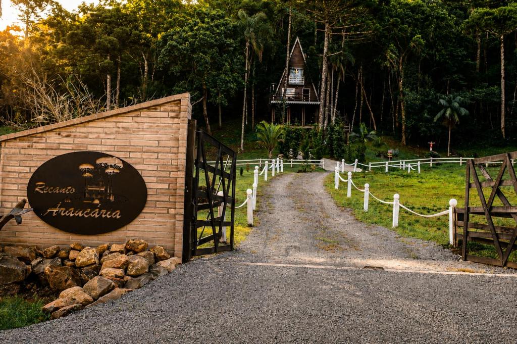 a gate with a sign next to a dirt road at Cabana Recanto da Araucária in Santa Cruz do Sul