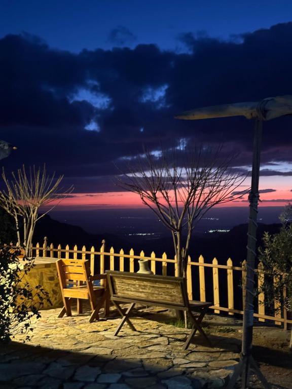 a wooden bench sitting next to a fence with an umbrella at Dana in Tufailah