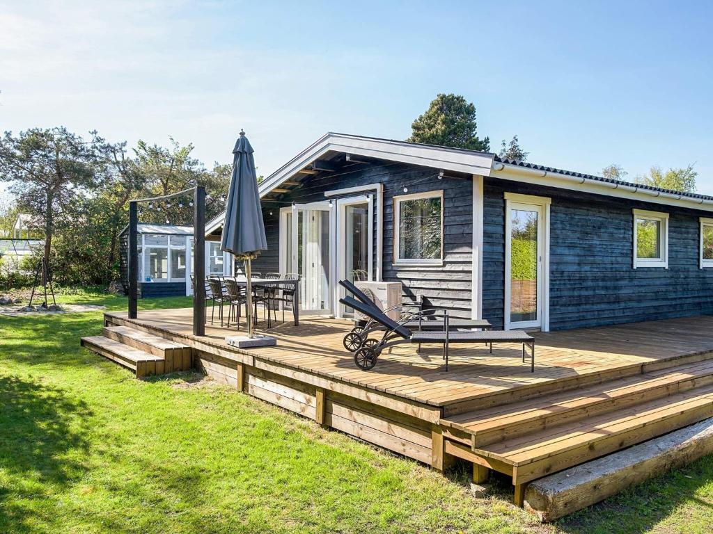 a wooden deck with an umbrella and a house at 4 star holiday home in Slagelse in Slagelse