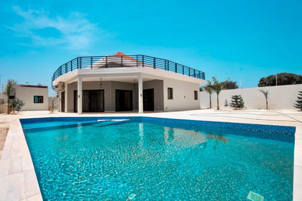 a villa with a swimming pool in front of a house at Le Refuge, Residence Ibrahima in Rufisque