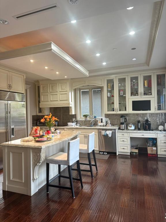 a kitchen with white cabinets and a island with chairs at Vancouver lovely home in Vancouver