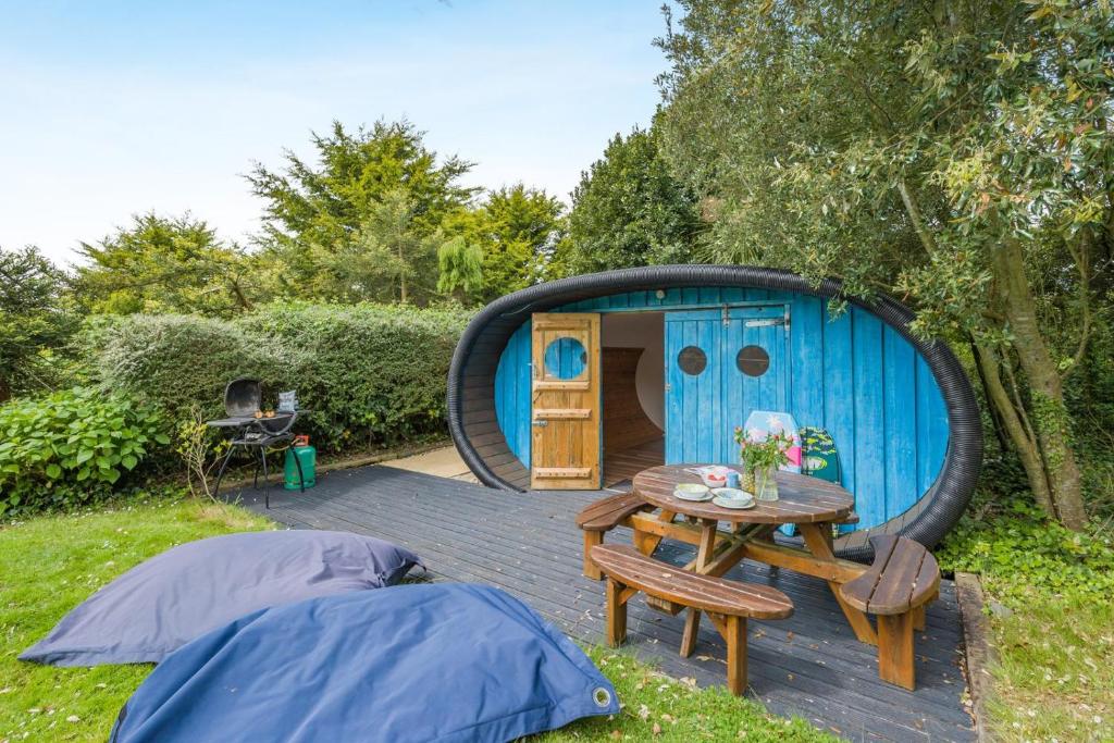 a small blue shed with a table and a tent at 1 Bed in Bude oc-s34851 in Bude