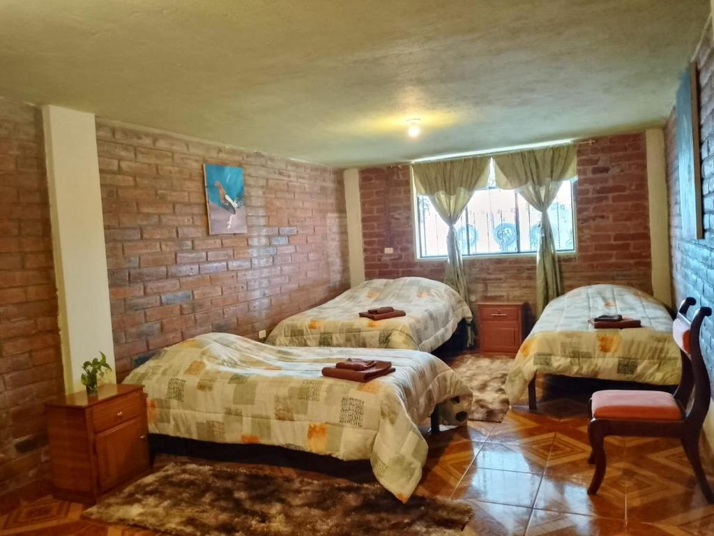 a bedroom with two beds and a brick wall at Casa del Sol Tumbabiro in Tumbabiro