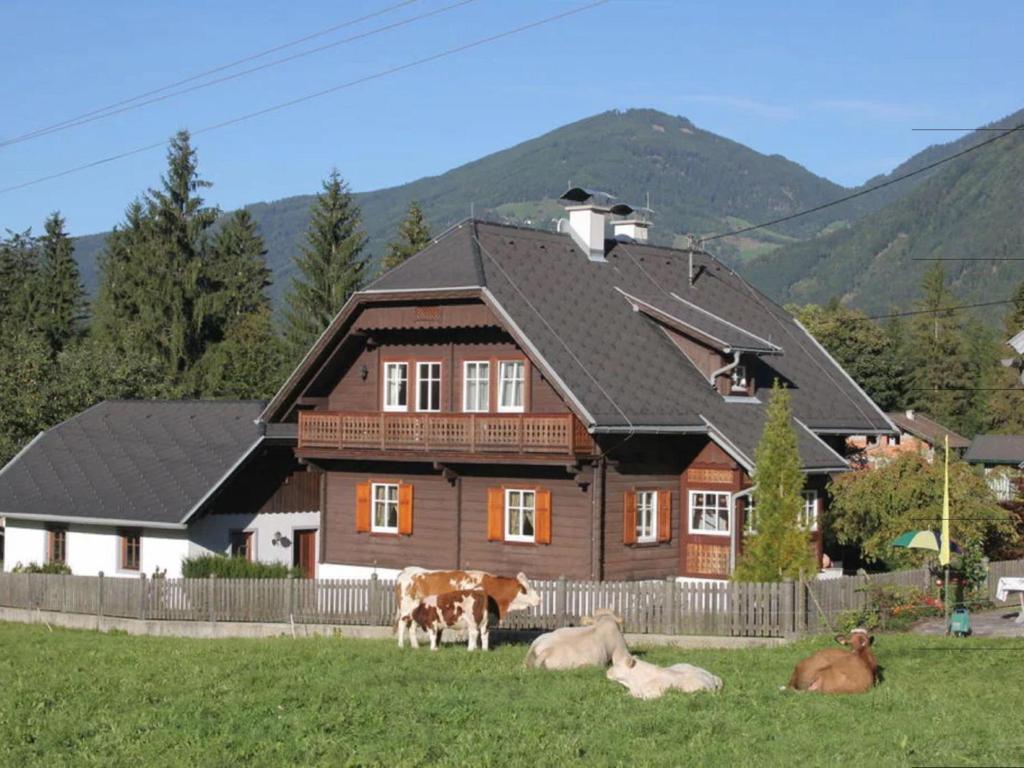 a house with three cows laying in the grass at Almenblick in Kleblach