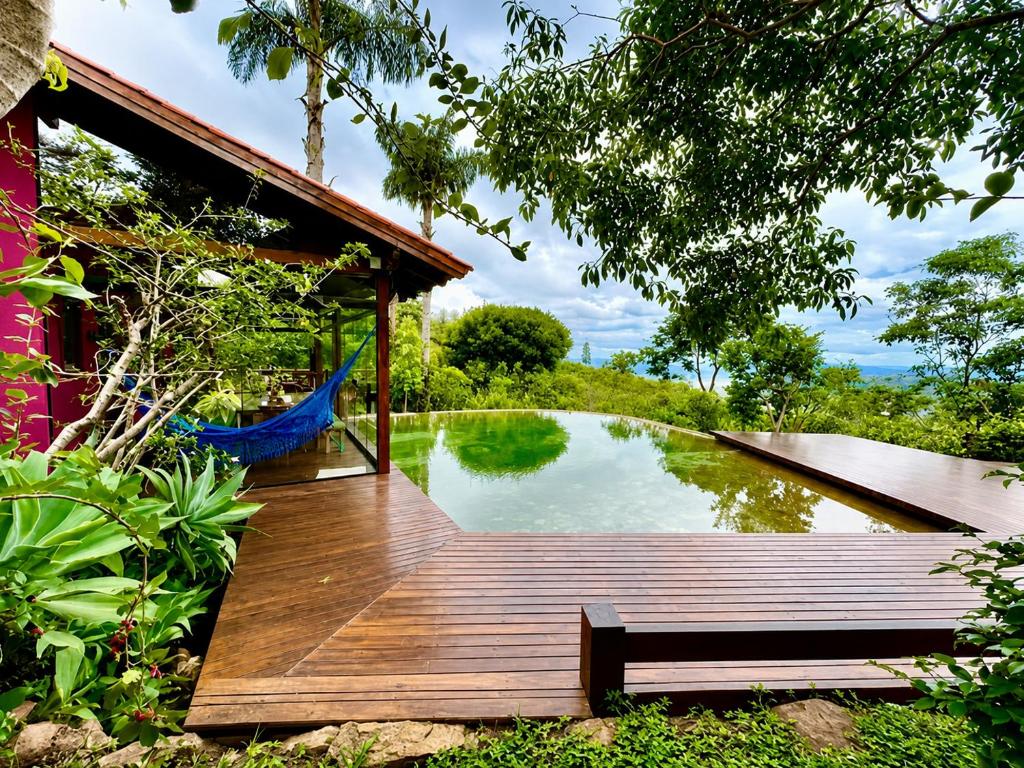 a wooden deck next to a pond with a hammock at Casa Rosa - Paraíso na Natureza piscina natural, Wi-Fi - 25 minutos do centro in Brasília