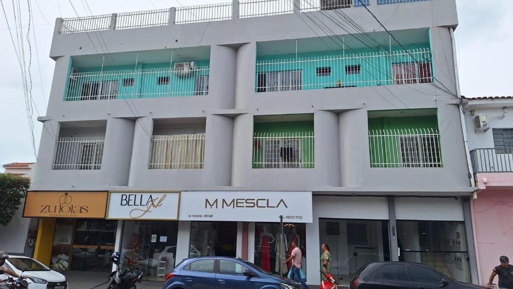 a large white building with cars parked in front of it at Apartamento no Centro Proximo a Tudo in Barra do Garças