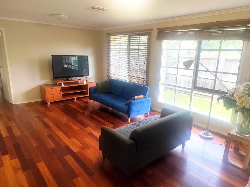 a living room with a blue couch and a tv at Spacious and cozy home next to Glen Waverley in Wantirna South