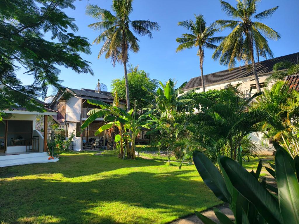 a yard in front of a house with palm trees at Kayu Cottage in Gili Trawangan