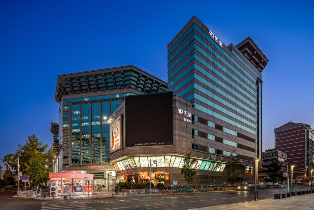a tall building with a clock in front of it at Beijing New World Centre Tongpai Hotel in Beijing