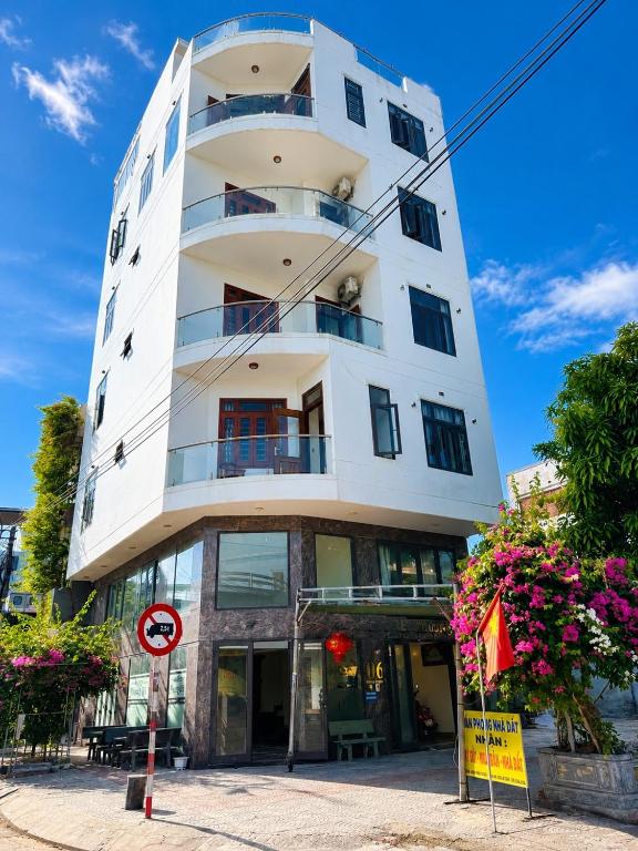 a tall white building with flowers in front of it at Phương Nhi Motel in Danang