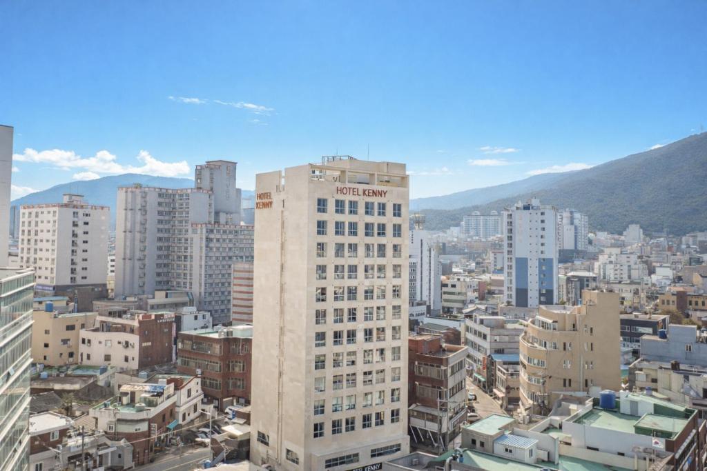 a tall white building in a city with buildings at Kenny Stay Busan Gijang in Busan