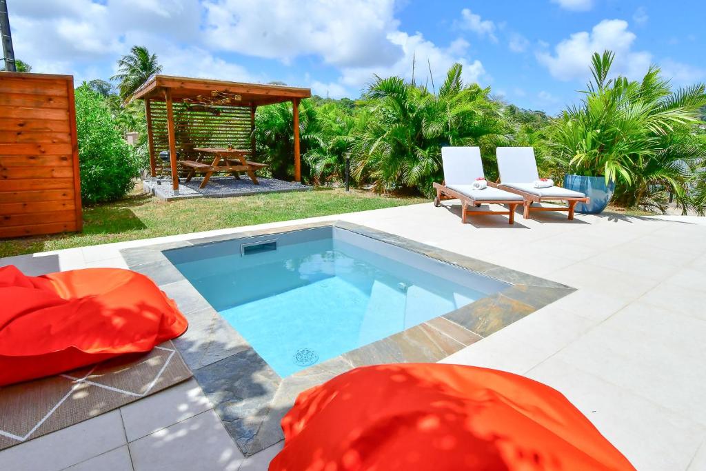 a swimming pool with two chairs and a gazebo at Dlo Lanmou in Ducos