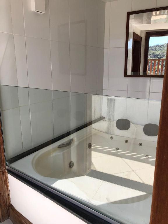 a white tub in a bathroom with a mirror at Cantinho do Rosário in Diamantina
