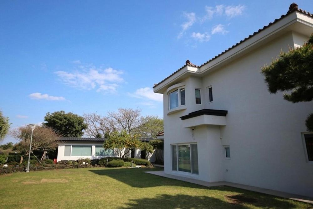 a white house with a grass yard at Maple Happy House Jeju in Jeju