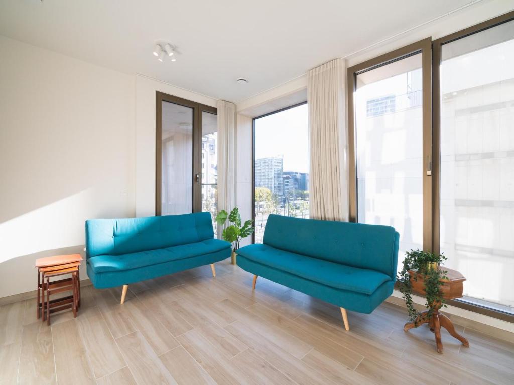 two blue chairs in a room with windows at City Hideaway with Terrace in Antwerp in Antwerp