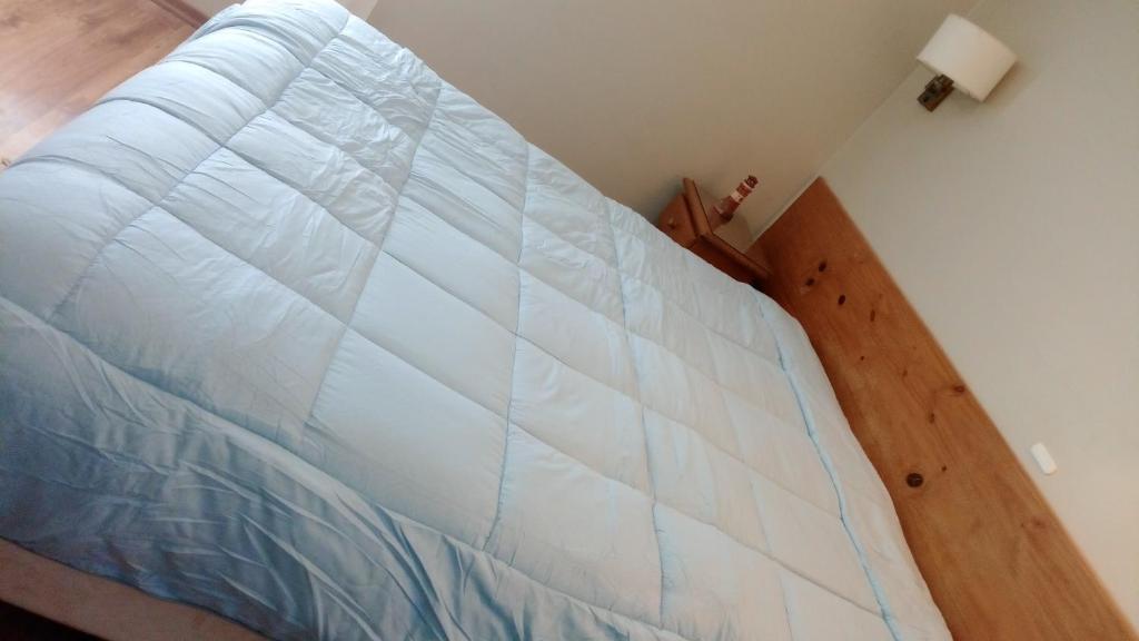 a large white bed in a room with a wooden floor at Depto en Edificio Céntrico in Trelew