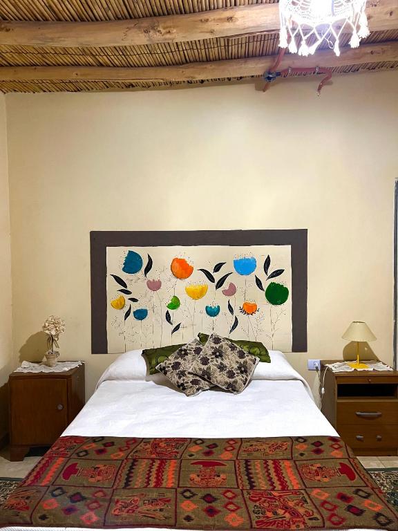 a bedroom with a bed with a painting on the wall at By Lela in Tinogasta