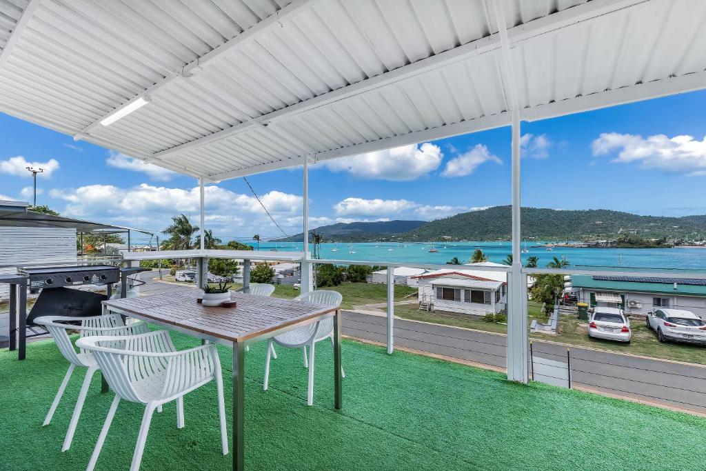 an outdoor patio with a table and chairs and a view of the water at Hillcrest Harmony in Airlie Beach