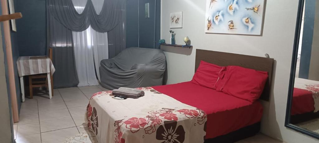 a bedroom with a bed with red sheets and red pillows at Pousada Paradise in Rio Grande