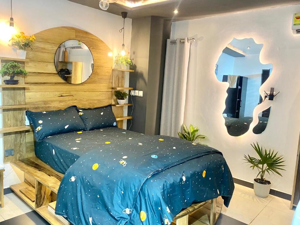 a bedroom with a blue bed and a mirror at Cozy Studio Apartment in Accra in Accra