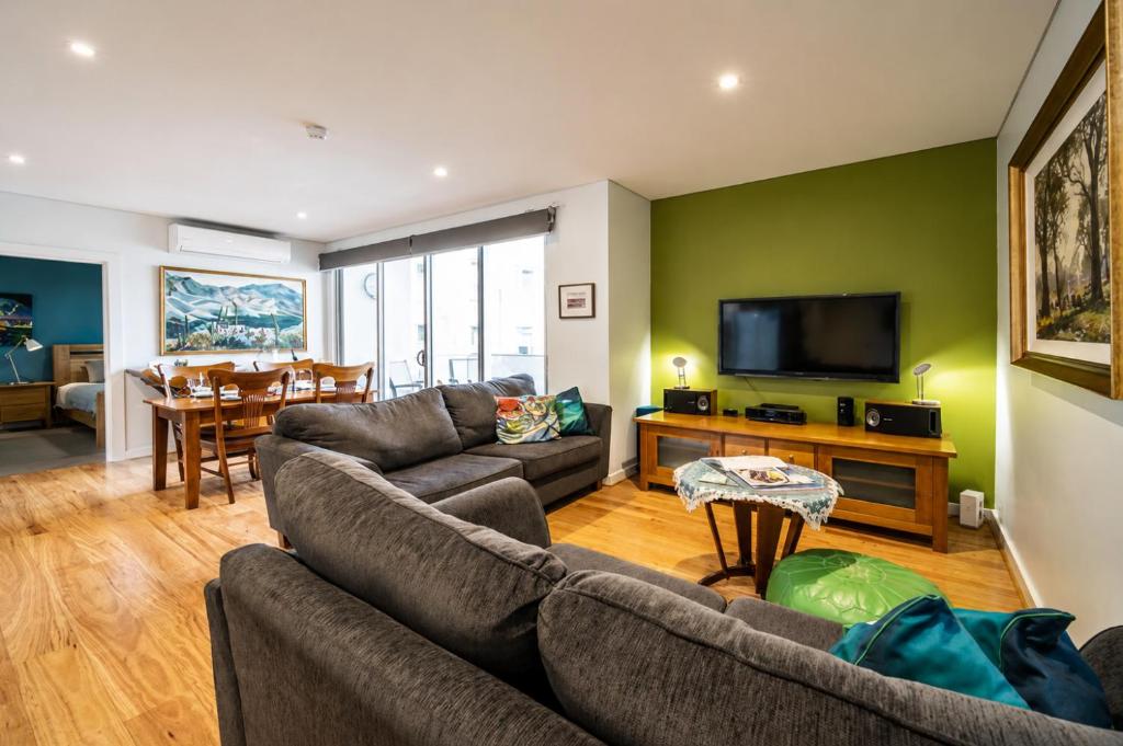 a living room with a couch and a television at Get Comfy on Frew - CBD Stay near Parklands & Dining in Adelaide