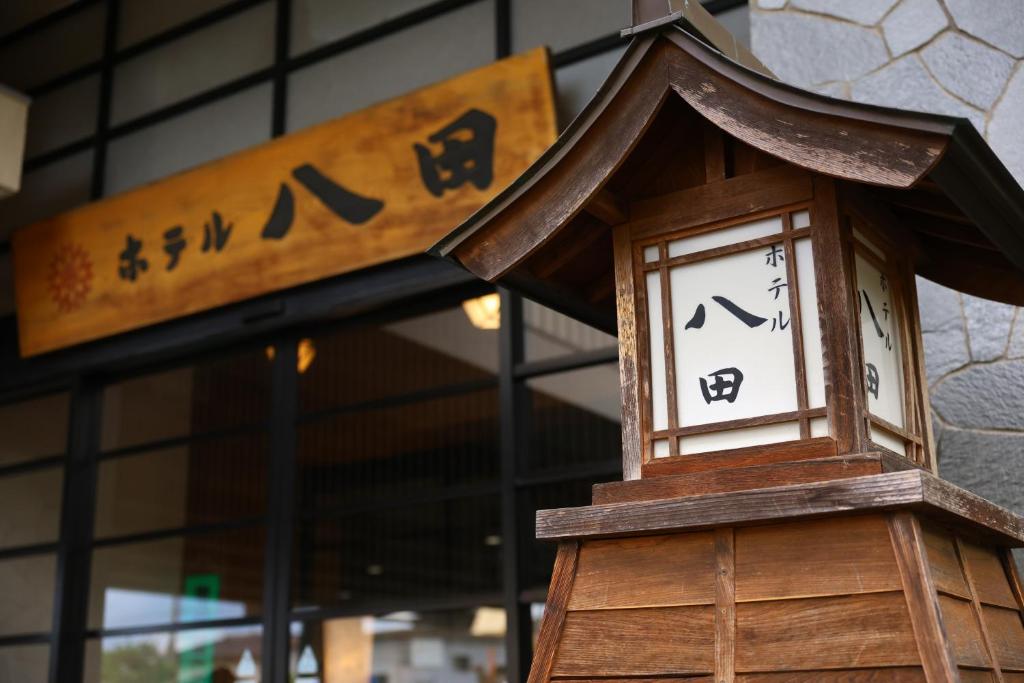 eine hölzerne Uhr, die vor einem Gebäude steht in der Unterkunft Hotel Hatta in Fuefuki
