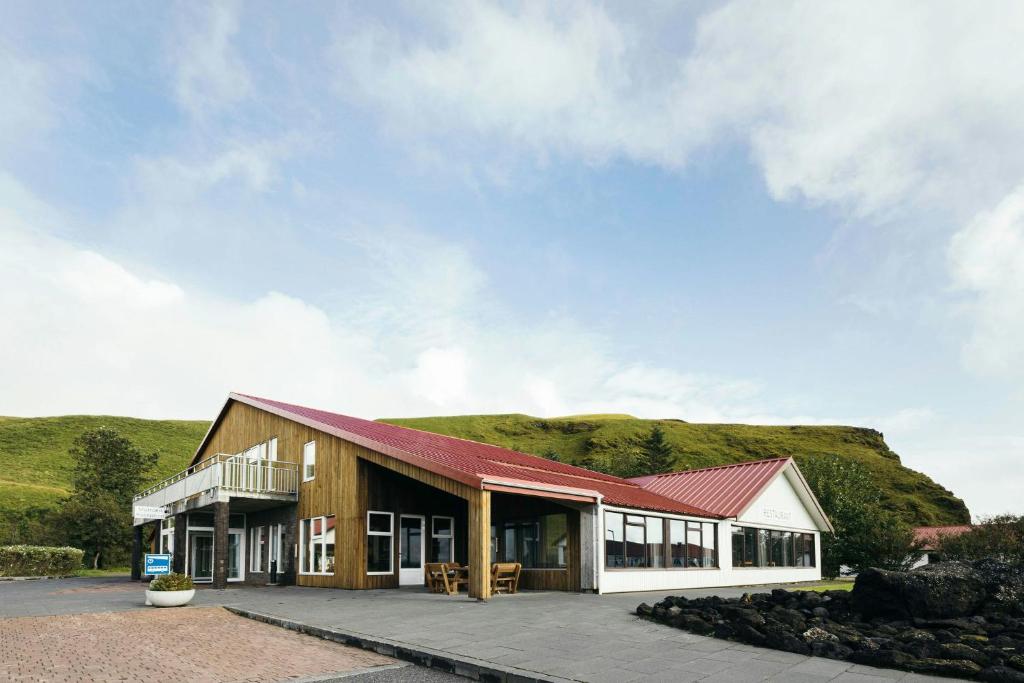 a barn with a hill in the background at Hotel Katla by Keahotels in Vík