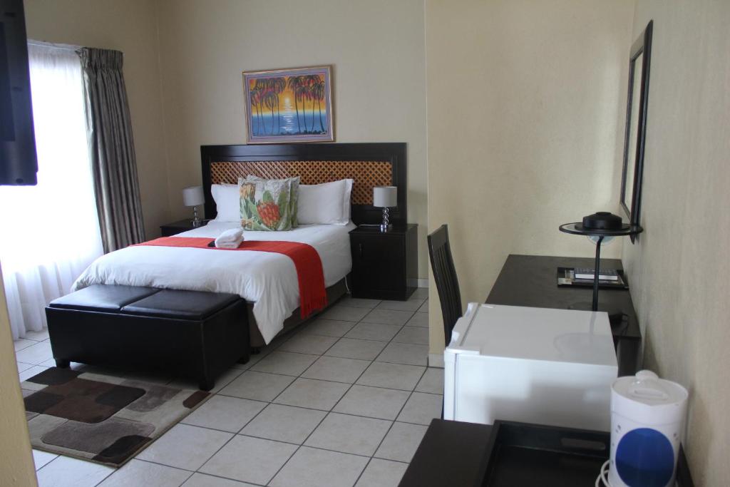 a bedroom with a bed and a table and a desk at Mcbest Guest House in Ermelo