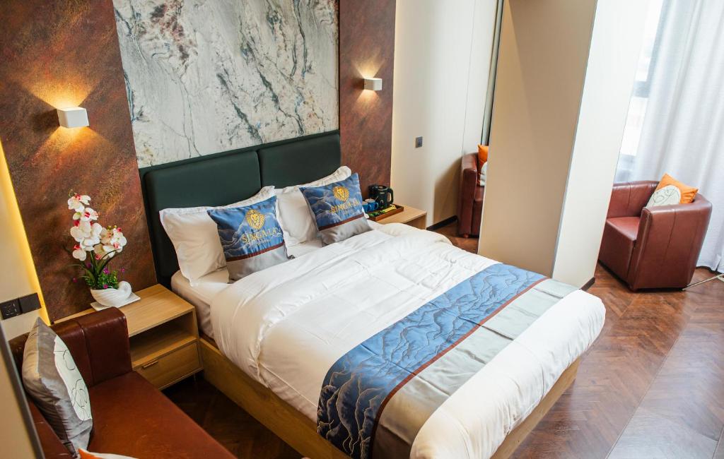 a bedroom with a large bed and a chair at Singala Hotel Ulaanbaatar in Ulaanbaatar