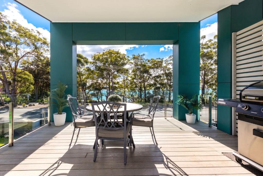 an outdoor deck with a table and chairs and a grill at Bruma on Bowen - Opposite Shark Net Beach in Huskisson