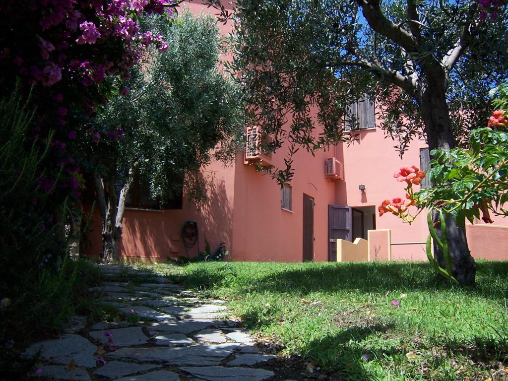 un chemin menant à une maison rose avec des arbres dans l'établissement Casa Vacanza Marina di Arbus, à Torre Dei Corsari