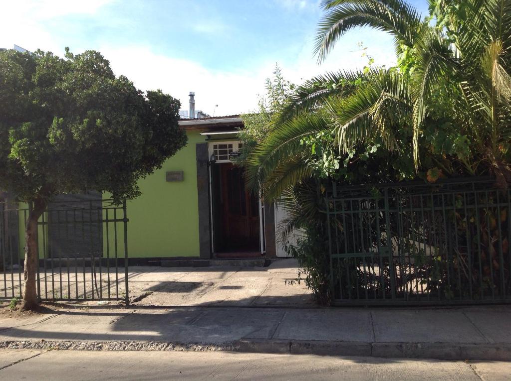 a green house with a gate and a palm tree at Hostel 1760 in Talca