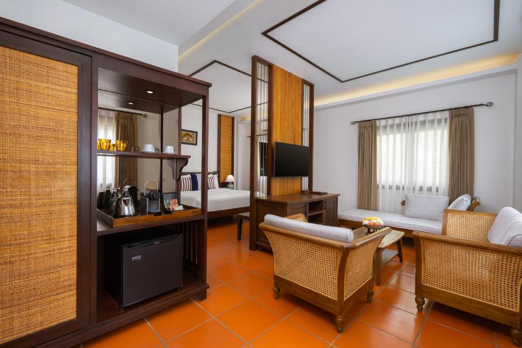 A suite-style sitting room separated from a bedroom by a decorative wood-and-metal partition.