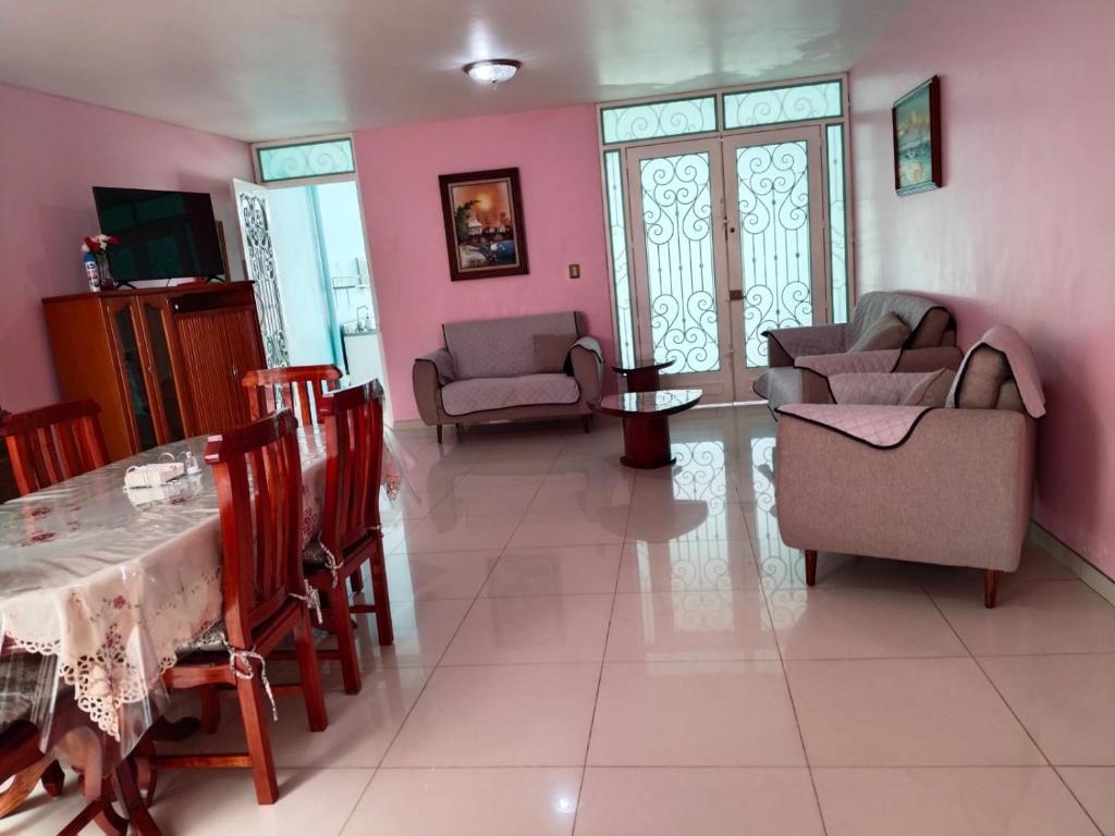 a living room with pink walls and a table and chairs at Casa céntrica en Morelia. in Morelia