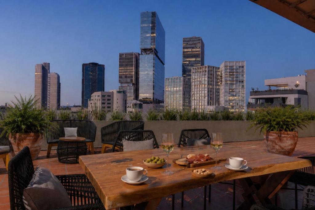a table with food and drinks on a balcony with a city skyline at DreamHaus Suites - Country Club Guadalajara in Guadalajara