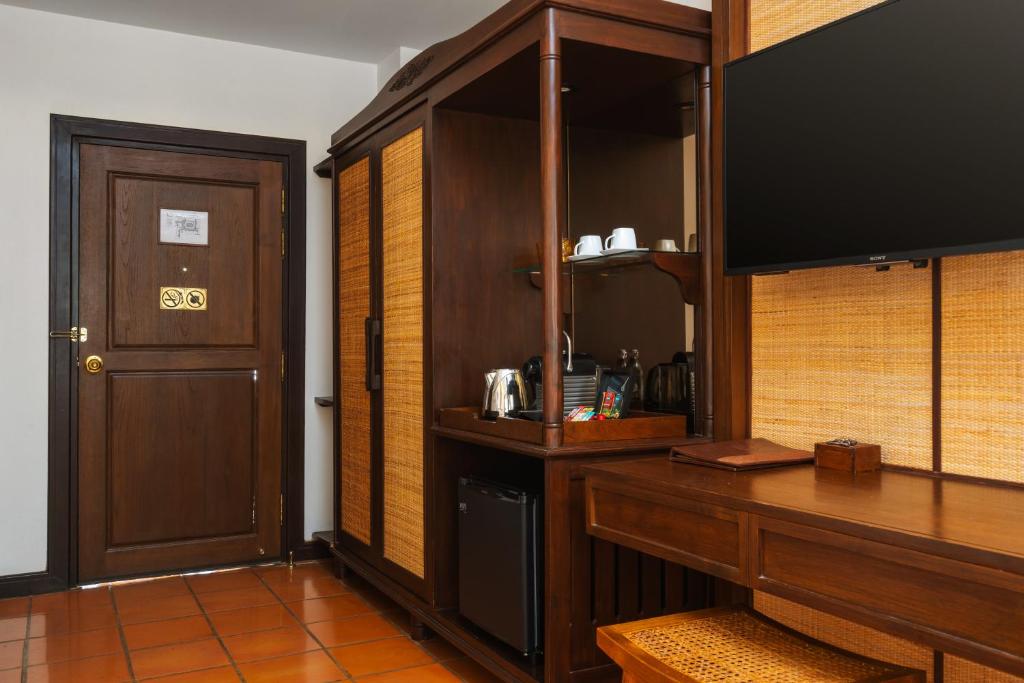 A compact wooden desk beside a television and in-room beverage station.